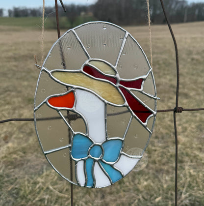 Stained glass duck with a red bow on a wire in a field