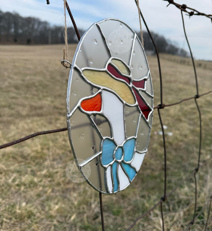 Stained glass duck decoration on a wire fence with a field in the background
